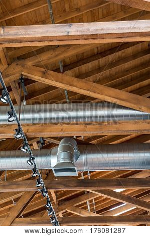 Ductwork and lights below a natural wood roof and rafters