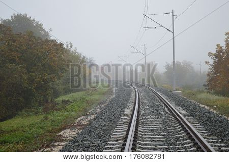 Railway track line in mist in autumn time