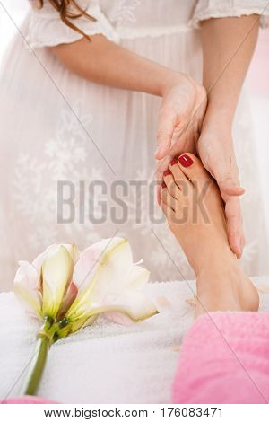 Closeup of female hands giving foot massage to lady after pedicure. Health and beauty concept.