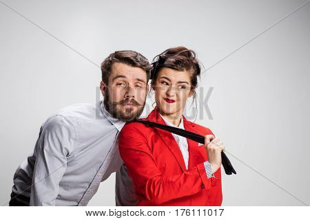 The funny business man and woman cooperating on a gray background. Business concept of leadership of colleagues