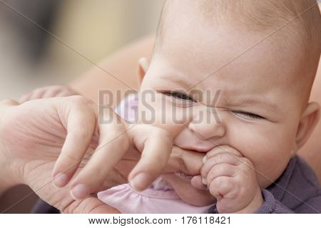 A ittle baby biting her mother finger