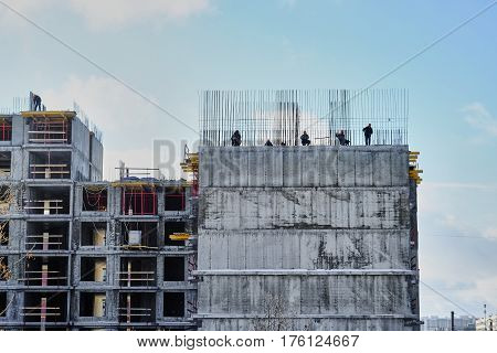 workers knit rebar standing on the edge of the house