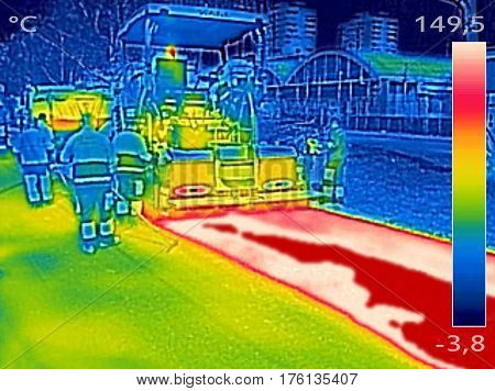 Infrared thermovision image showing Workers on Asphalting paver machine during Road street repairing works