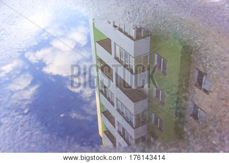 Water reflection house in the puddle. Apartment building is reflected in the water. The forms of objects distorted