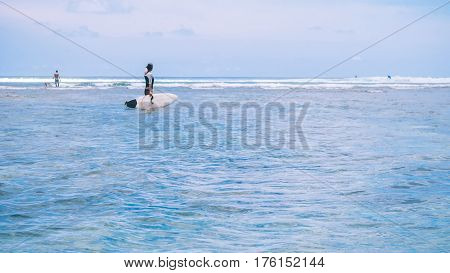 Silhouette of Fit woman going to surf in sea and looking to wave edge on horizon at Bali island, Indonesia.