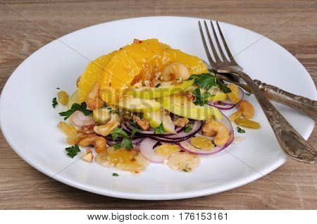 Salad with slices of orange apple blue onion raisin nuts cashew nuts herbs and honey sauce