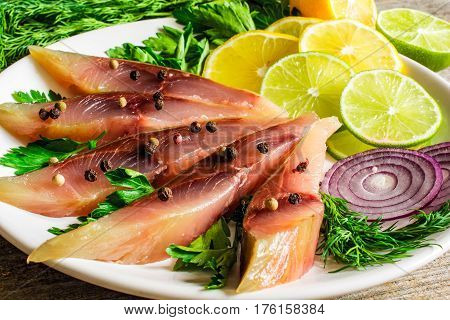 salted fish fillet with herbs lemon and spices in a plate. close up