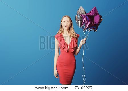 Valentine's Day. Woman in red dress holding balloons on the blue background. Processed with VSCO s3 preset
