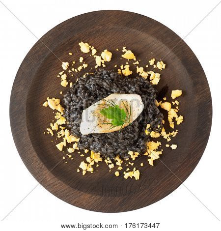 Black squid ink risotto with seared calamar on round wooden plate isolated on white