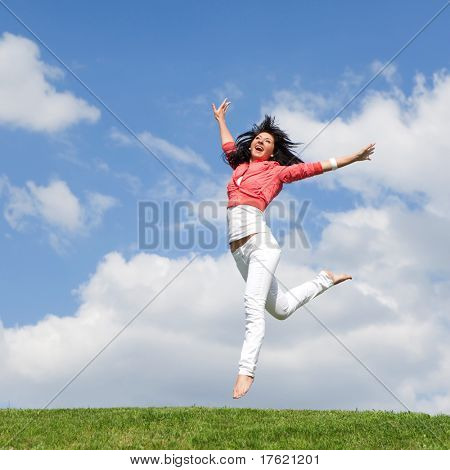pretty young woman jumping on green grass
