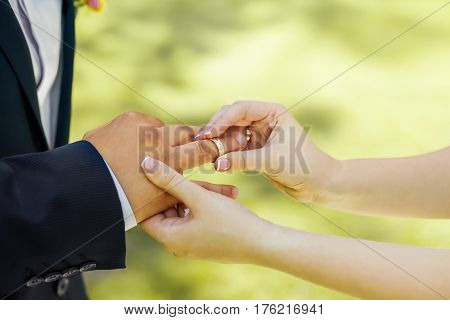 Newlyweds staying arm in arm, with wedding rings, closeup