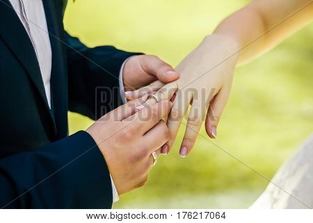 Newlyweds staying arm in arm, with wedding rings, closeup