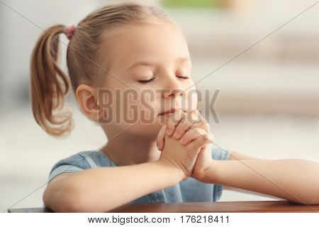 Cute little girl praying at home