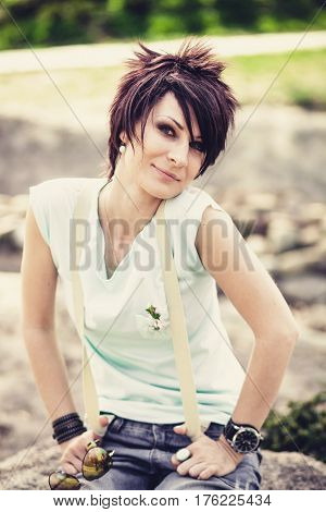 Young beautiful woman with short hair sitting on a stone. Spring. Romantic style