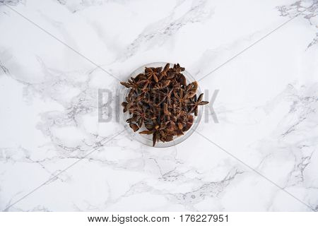 Chinese star anise or badiam seeds in a bowl on white marble table
