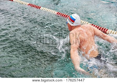 SAHYURTA IRKUTSK REGION RUSSIA - March 11.2017: Cup of Baikal. Winter Swimming Competitions. Butterfly. One man on the water path from back