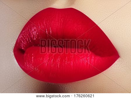 Cosmetics makeup and trends. Bright lip gloss and lipstick on lips. Closeup of beautiful female mouth with red lip makeup. Beautiful part of female face. Perfect clean skin. Valentine sweet kiss