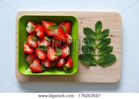 Fresh strawberry with leaves of mint on the white background.