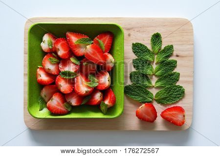 Fresh strawberry with leaves of mint on the white background.