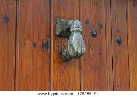 Door knocker in the form of a hand on wooden door in Rupit (Catalonia Spain)