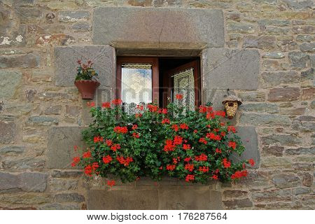 Window with white curtains birdhouse hanging pot and decorated Geranium flowers in Rupit (Catalonia Spain)