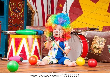 Little baby clown with red nose multi-colored wig in with balls.