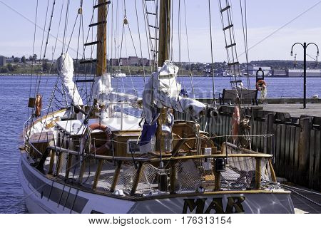 Halifax, Nova Scotia, September 23, 2015 -- Wide view of a wood trimmed sail boat docked at the Halifax Harbor on a beautiful bright sunny day in September with Dartmouth buildings in the background in Halifax, Nova Scotia
