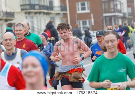 BRIGHTON GREAT BRITAIN - FEB 26 2017: Man without shirt and red skin running in the Vitality Brighton half marathon competition. February 26 2017 in Brighton Great Britain