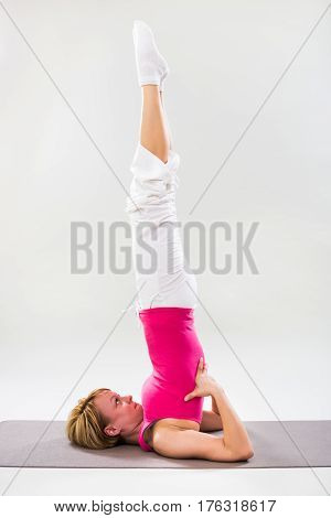 Photo of woman exercising yoga indoor-Supported Shoulderstand/Salamba Sarvangasana