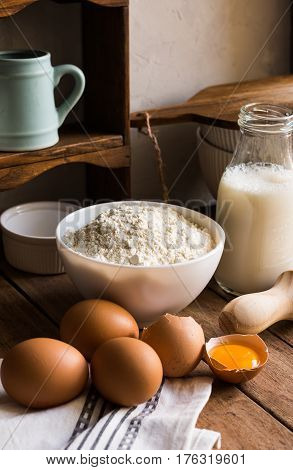 Baking ingredients flour milk eggs rolling pin on wood kitchen table rustic interior cozy homely atmosphere
