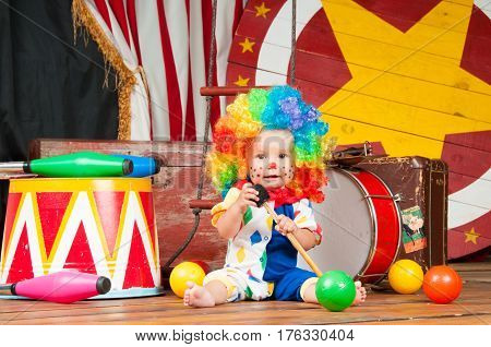 Little baby clown with red nose multi-colored wig in with balls.