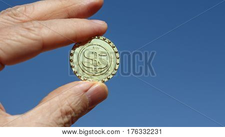 A newly minted bitcoin virtual currency unit held up to a blue sky