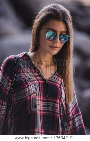 Outdoor fashion image of stylish young lady, fashionable.Lifestyle portrait of stunning hipster girl, wearing elegant glamour shirt dress and vintage sunglasses.