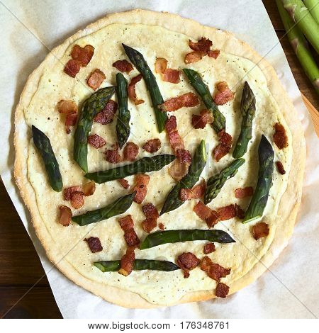 Green asparagus and bacon tarte flambee or Flammkuchen a typical Alsatian and South German dish photographed overhead with natural light