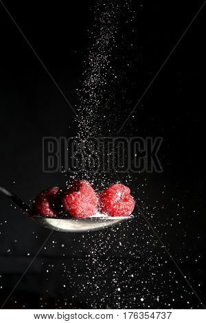 a photo of raspberries with sugar being sprinkled on them