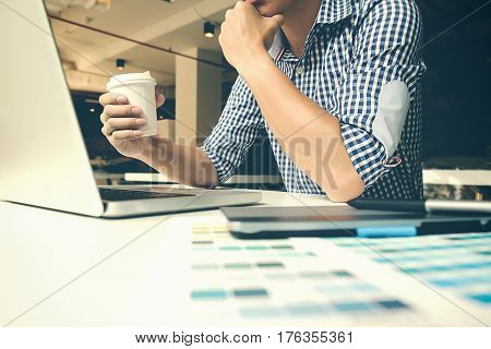 Concentrated at work. Confident young man in smart casual wear working on laptop while sitting near window in creative office or cafe