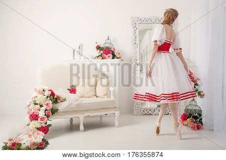 A sweet ballerina in a stage suit in front of a mirror. Retro dress.