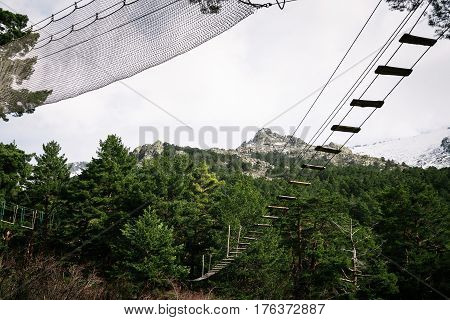 Zip line in woodland against snow capped mountain range. Navacerrada Madrid Spain