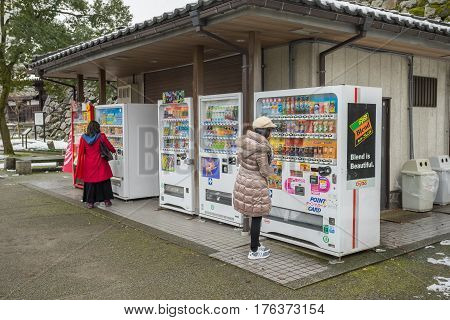 TOYAMA, JAPAN - FEB 13, 2017: Some people buying some drink with Vending machines in front of Toyama castle in Toyama city, Japan