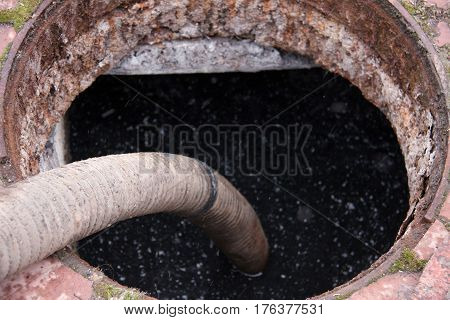 man pumping sewage from the drain hole.