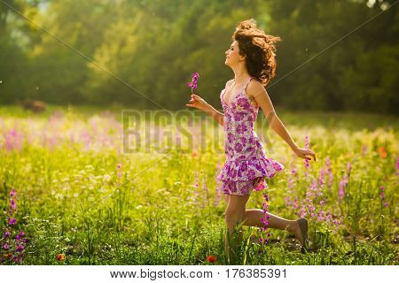 Beautiful young woman running in purple flowers outdoors