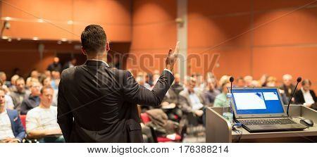 Speaker giving a talk on corporate business conference. Audience at the conference hall. Business and entrepreneurship event.