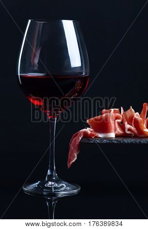 Prosciutto And Red Wine On A Black  Background