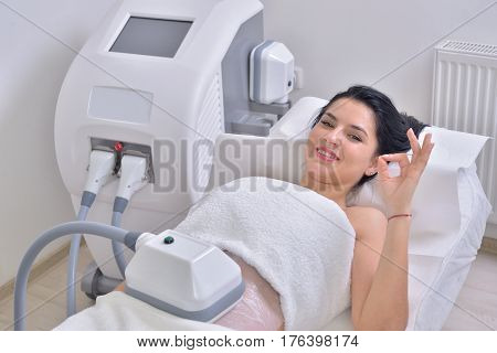 Pretty young woman getting cryolipolyse fat treatment in professional cosmetic cabinet