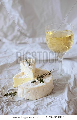 Brie cheese on wrapping paper with thyme herbs