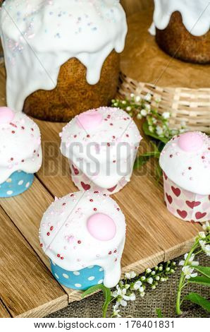 Easter cakes with white glaze on wooden table. Selective focus