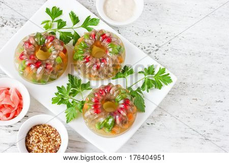Beef aspic with pomegranate green peas carrot and parsley. Beautiful festive appetizer on a white background with blank space for text top view