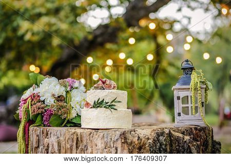 Beautiful wedding decoration with cake bouquet of flowers and a lantern on background of nature