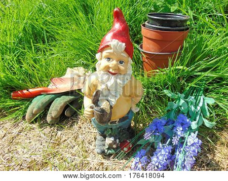 Garden gnome surrounded by grass and tools