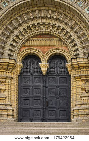Steps leading up to the entrance of a beautiful church with doors by the stairs.